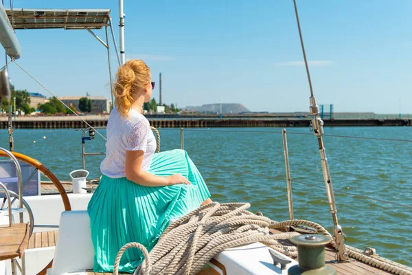 Etrafa bir yatın güvertesinde oturan bir kız