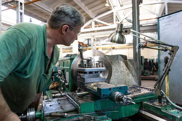 Worker, a man processes metal products on a machine. Turning work in production