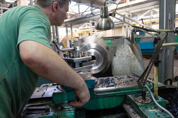 Working man manages the equipment of the cutting machine. Turning work in production