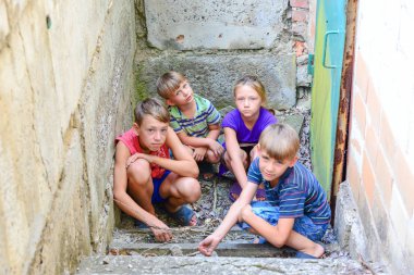 Bodrum katında çocuklar, üç erkek ve bir kız demir kapının yanında dış dünyadan basamaklarda saklanıyorlar. Post-Prodüksiyon fotoğraf.