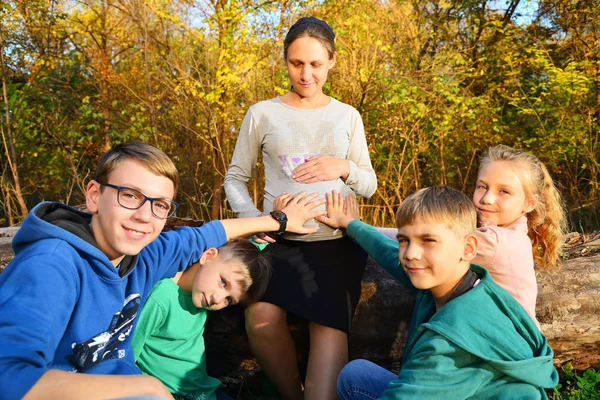 Czworo Dzieci Szukają Aparatu Małe Dzieci Siedzą Obok Kobiety Ciąży — Zdjęcie stockowe