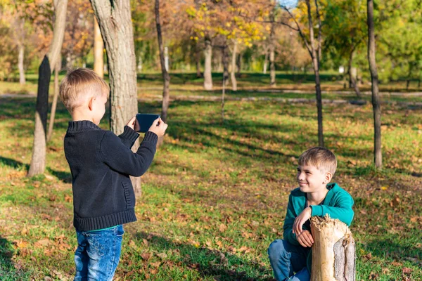 Niño Toma Fotos Teléfono Inteligente Hermano Parque Día Soleado —  Fotos de Stock