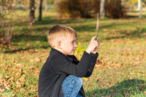 Küçük Bir Çocuk Parkta Telefonda Güneşli Bir Günde Fotoğraf Çeker — Stok fotoğraf