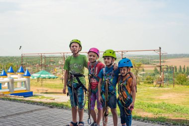 Four children are wearing helmets and climbing clothes and are ready to overcome obstacles in an extreme park clipart