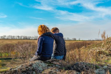 Bir erkek ve bir kız bir uçurum, iki arkadaş, bir ve bir kız üzerinde oturmuş, birbirlerine sarılıyorlar