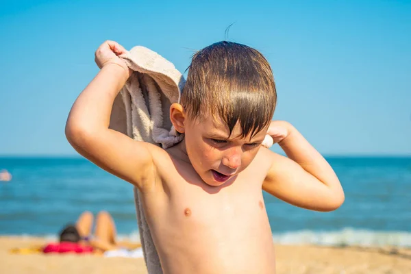 少年は 日当たりの良い夏の日に彼自身 海岸でタオルで覆われて — ストック写真