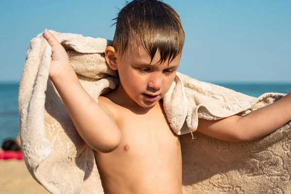 少年は 日当たりの良い夏の日に彼自身 海岸でタオルで覆われて — ストック写真