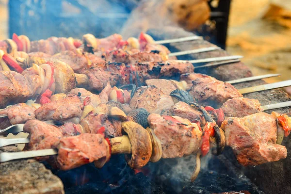 Kızarmış ve mantar ile sulu et şiş bir yanıyor, şişleri onları yanan Odun kömürleri altında tuğla üzerinde kızarmış. Kızarmış et ve yemeği ızgara üzerinde mantar