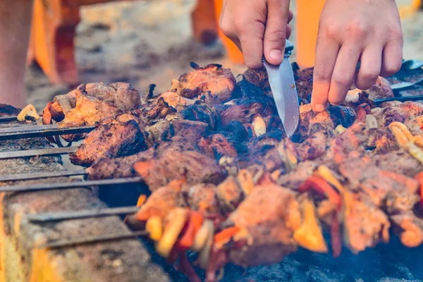 一名男子用烤肉串将烤肉串切碎 用刀切肉 用洋葱 蘑菇和肉烧烤 — 图库照片