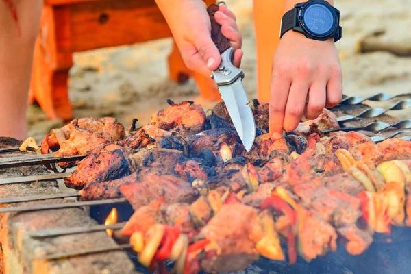 一名男子用烤肉串将烤肉串切碎 用刀切肉 用洋葱 蘑菇和肉烧烤 — 图库照片