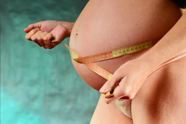 Dziewczyna Ciąży Różowe Majtki Niebieskim Tle Pomiar Objętości Brzucha Taśmą — Zdjęcie stockowe