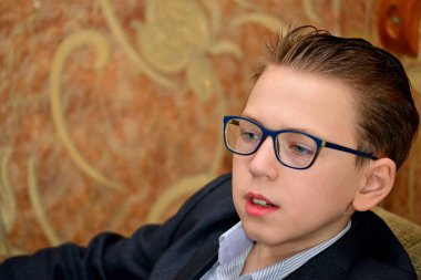 Bir çocuk gözlük ve bir takım elbise ile yakından görünüyor.