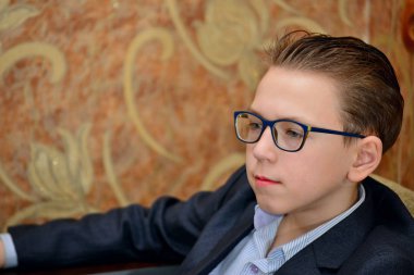 Bir çocuk gözlük ve bir takım elbise ile yakından görünüyor.