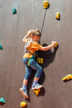 Korkmuş küçük bir çocuk, bir emanet ip ile yapay bir kayaya tırmanmak istiyor kaya tırmanışı devreye girer