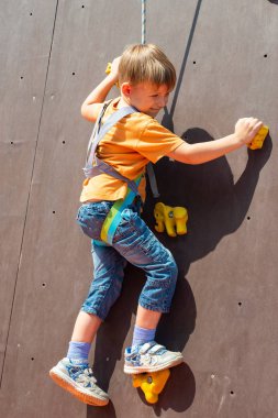 Korkmuş küçük bir çocuk, bir emanet ip ile yapay bir kayaya tırmanmak istiyor kaya tırmanışı devreye girer