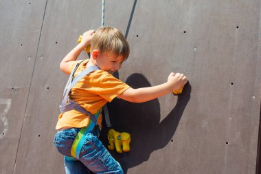 Korku içinde ve mutlu küçük çocuk bir emanet ip ile bir yapay kaya taşıyan kaya tırmanışı meşgul