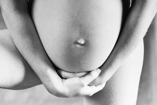 性感怀孕的女孩特写 在一个黑色的 T恤举行她的手下腹部 黑白照片 — 图库照片