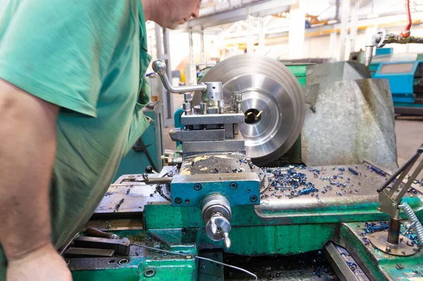 İşçi, bir adam bir makine üzerinde metal ürünler işler. Üretim çalışmalarında dönüm