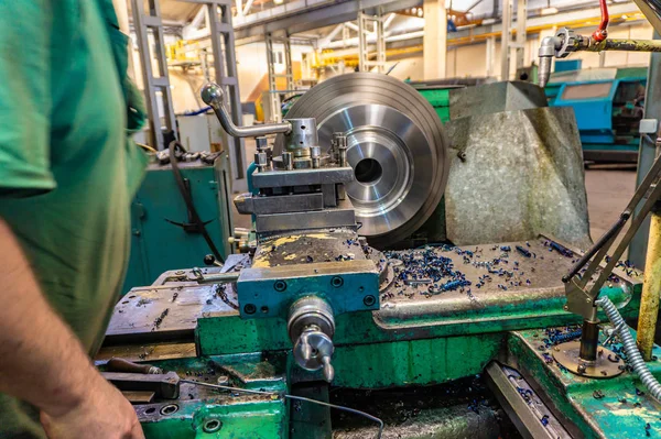İşçi, bir adam bir makine üzerinde metal ürünler işler. Üretim çalışmalarında dönüm
