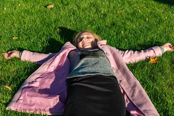 Lány Rózsaszín Kabát Ősszel Zöld Gyep Parkban Fekszik — Stock Fotó