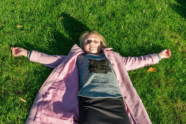 Lány Rózsaszín Kabát Ősszel Zöld Gyep Parkban Fekszik — Stock Fotó