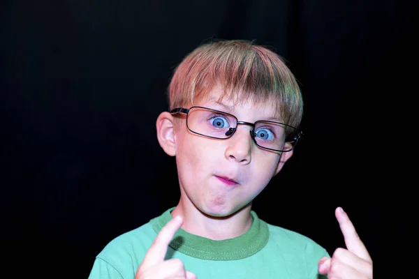 Chłopiec Dorywczo Okulary Pokazuje Różne Twarze Aparatu Ciemnym Tle — Zdjęcie stockowe