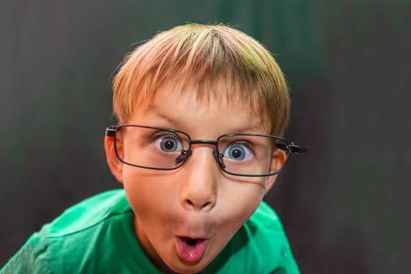 Chłopiec Dorywczo Okulary Pokazuje Różne Twarze Aparatu Ciemnym Tle — Zdjęcie stockowe