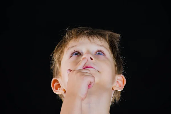 Chłopiec Dłubie Nosie Spogląda Górę Czarnym Tle — Zdjęcie stockowe
