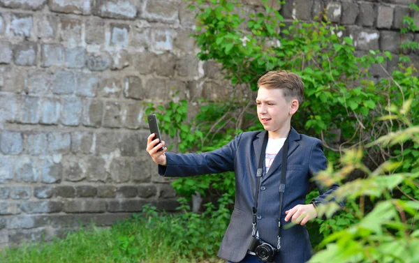 一个拿着相机的男孩在智能手机上 在街上做自拍 — 图库照片
