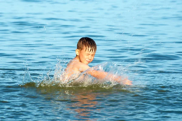 夏天的一天 男孩在海水中洒在海洋上 向幸福和快乐的方向挥动双臂 — 图库照片