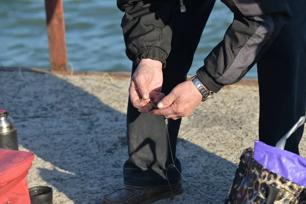 男は釣りのための釣り竿のフックにワームを引く — ストック写真