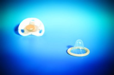 Bebek meme ve prezervatif üzerinde mavi arka plan, sağlıklı cinsel kavramı ve çocuk doğum