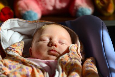 Yeni doğmuş bir bebek yatıyor ve bir bebek arabası çocuk yumuşak oyuncaklar arka planı içinde uyur