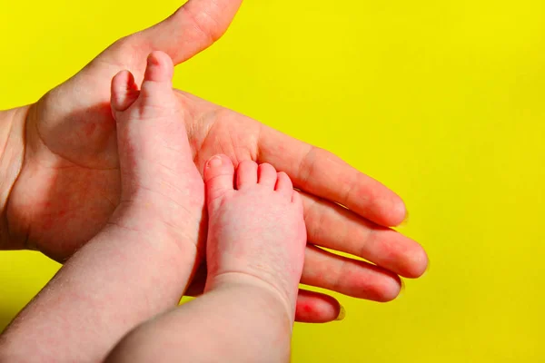 Babybeine Auf Gelbem Hintergrund Die Mutter Hält Die Kleinen Beine — Stockfoto