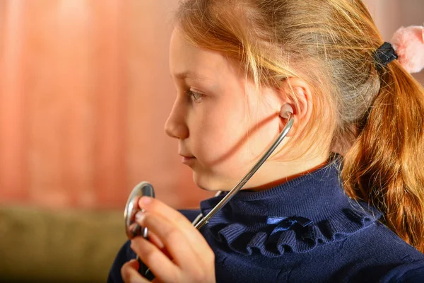 一个女孩手里拿着听诊器 听病人说话 家里的比赛在医生那里 — 图库照片