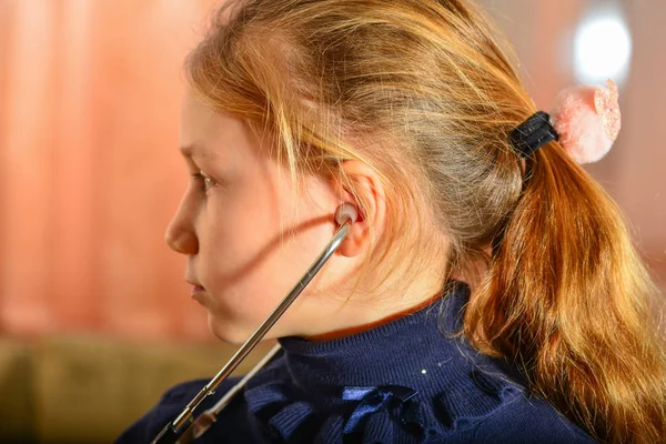 一个女孩手里拿着听诊器 听病人说话 家里的比赛在医生那里 — 图库照片
