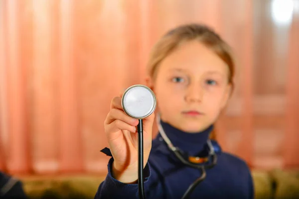 Dziewczyna Trzyma Stetoskop Jego Ręce Pokazuje Aparatu Domu Gry Lekarza — Zdjęcie stockowe