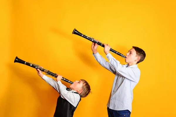 Due bambini che suonano il clarinetto, su uno sfondo giallo — Foto Stock