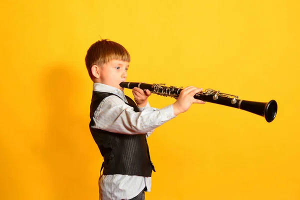 Ένα μικρό αγόρι σε ένα κοστούμι παίζει το κλαρινέτο — Φωτογραφία Αρχείου