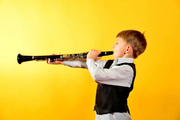 Um rapazinho de fato toca clarinete. — Fotografia de Stock