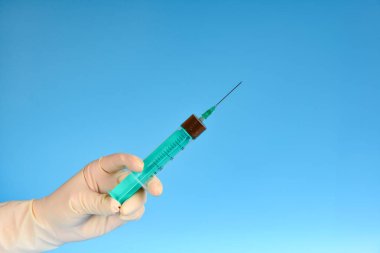 Doktor yeşil şırıngayla tıp Medikal Ürünler mavi bir arka plan üzerinde tutar