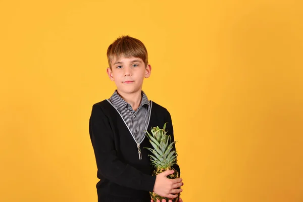 Söt pojke drog ananas mot gul bakgrund — Stockfoto