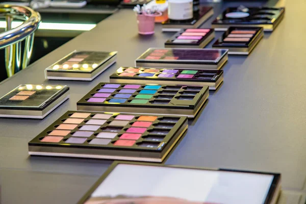 Sombra de ojos multicolor, rímel, lápiz labial, cosméticos faciales en el mostrador de la tienda en el centro comercial —  Fotos de Stock