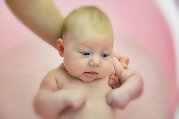 Мама купает новорожденного в розовой ванне, крупным планом — стоковое фото