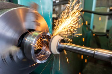 Sonunda işlenmesi nedeniyle oluşan bir metal yüzeye dokunarak bir zımpara taşlı yuvarlak taşlama tezgahı, farklı yönlere kıvılcım sinek.