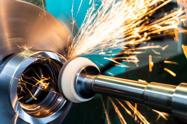 End processing of a metal surface with an abrasive stone on a circular grinding machine, sparks fly in different directions.