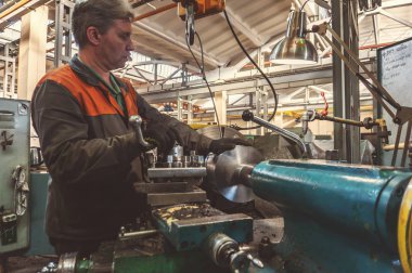 Turner çalışan bir Torna üzerinde mekanik kesme metal işleme sürecini yönetir.