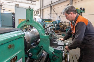 Turner çalışan bir Torna üzerinde mekanik kesme metal işleme sürecini yönetir.