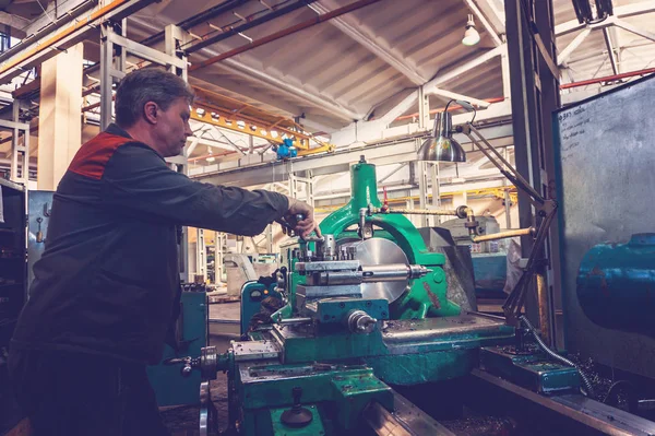 Turner werknemer beheert het proces van de metaalbewerking van mechanische snijden op een draaibank. — Stockfoto