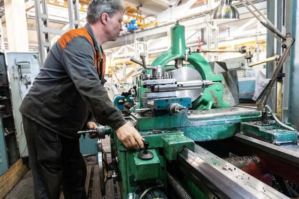 Turner werknemer beheert het proces van de metaalbewerking van mechanische snijden op een draaibank. — Stockfoto